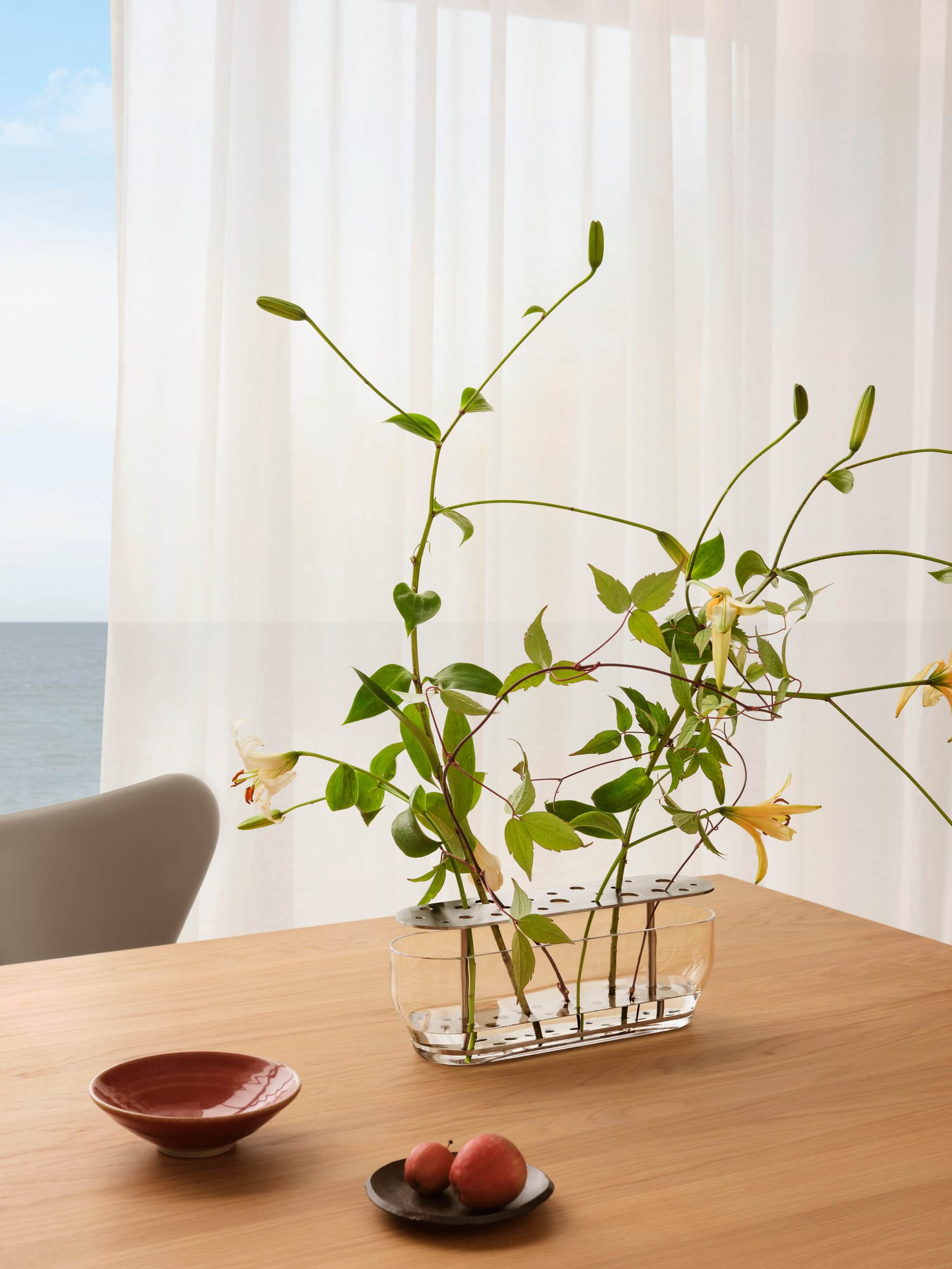 Vaso Ikebana comprido com flores, sobre uma mesa de madeira