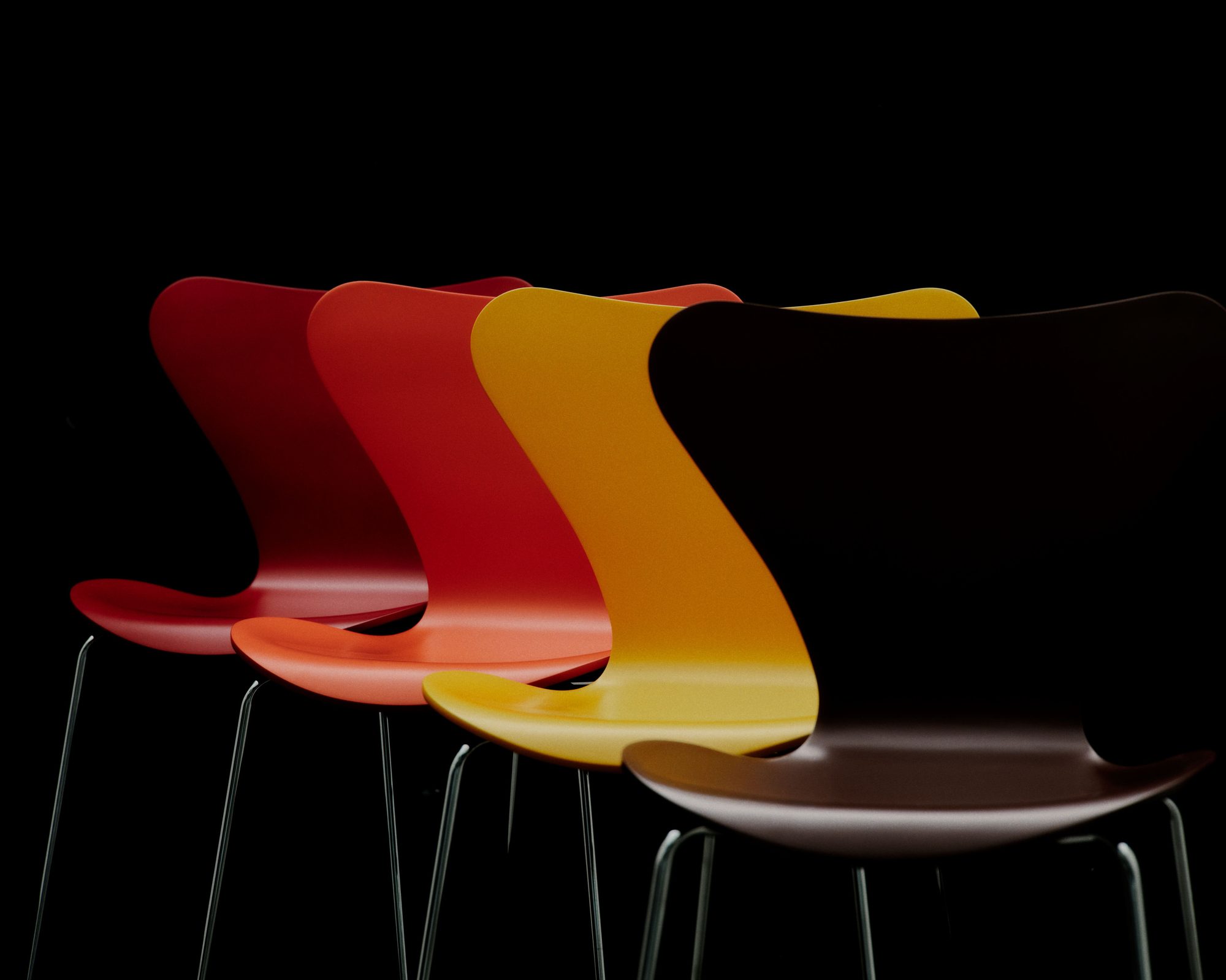 Cadeiras Series 7 de Arne Jacobsen em várias cores, alinhadas sobre fundo preto