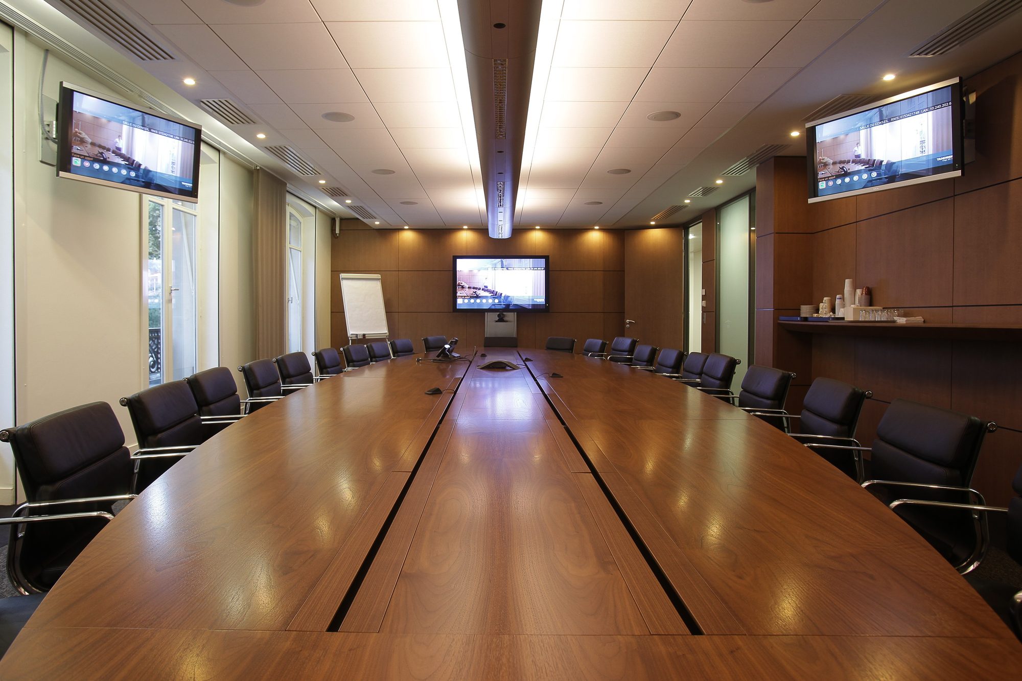 Sala de conselho com mesa In-tensive à medida em madeira, com calha dupla e ecrãs
