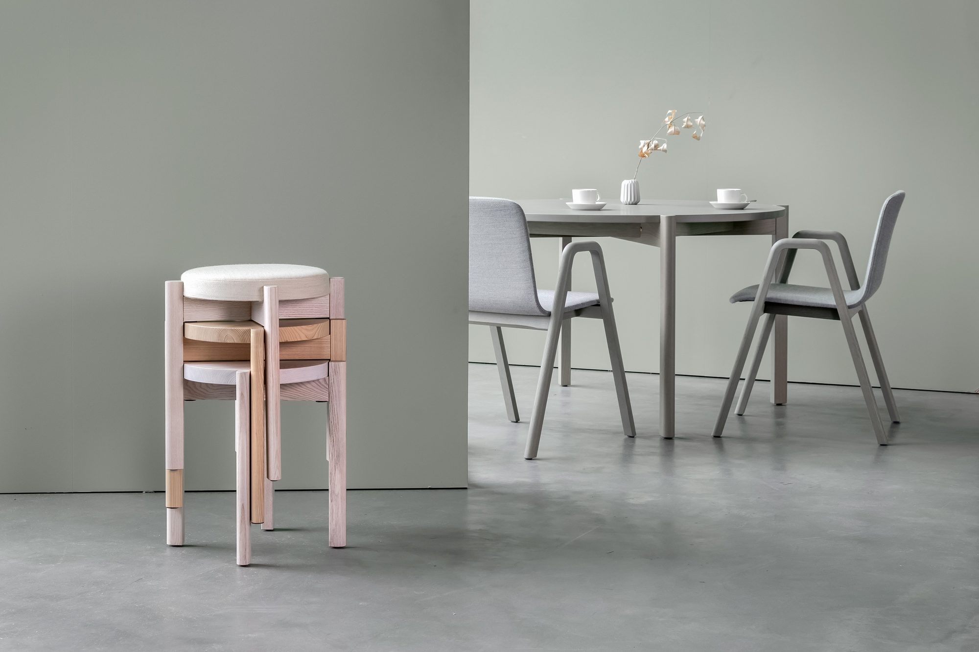 Bancos Naku Stool empilhados junto de cadeiras e mesa Naku